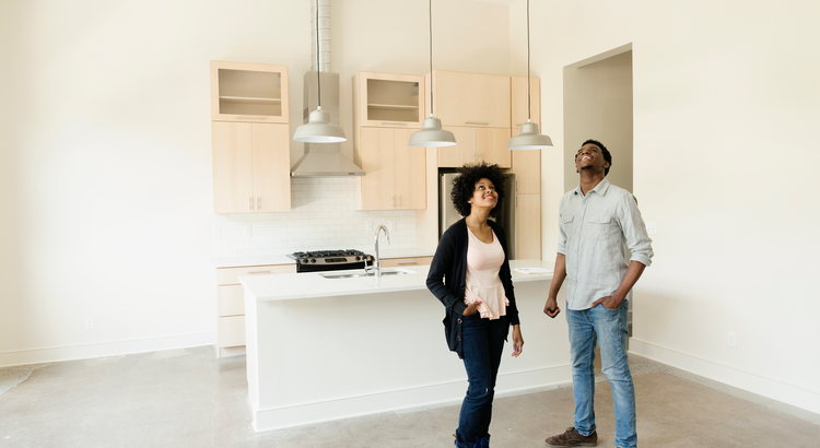 Man and woman standing in empty kitchen looking at ceiling