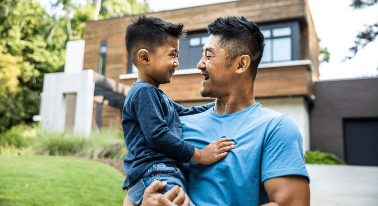 Dad and son in front of new home celebrating homeownership