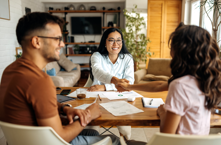 Agent smiling and shaking the hands of new clients after a confident conversation