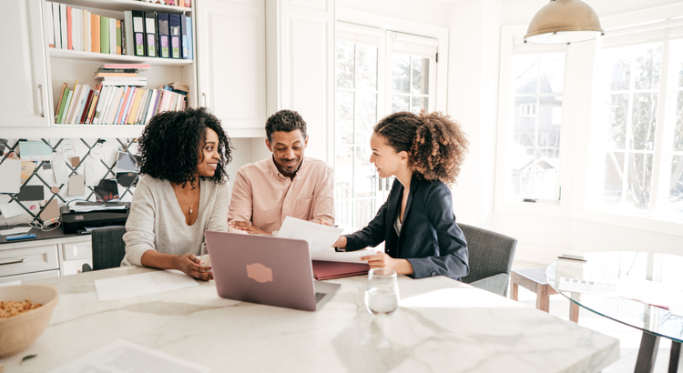 Agent sitting down to educate two clients in a kitchen.